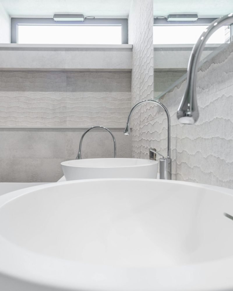 White ceramic sinks and chrome faucets installed in modern bathroom with light gray walls in contemporary luxury house